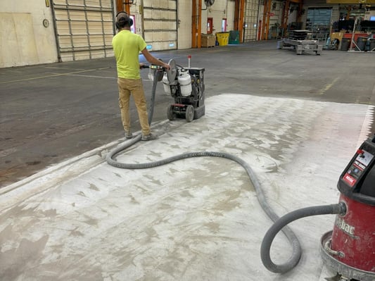 A large commercial grinder removing the top layer of concrete.