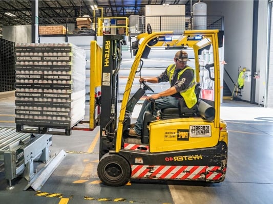 A worker driving a forklift on a loading dock.