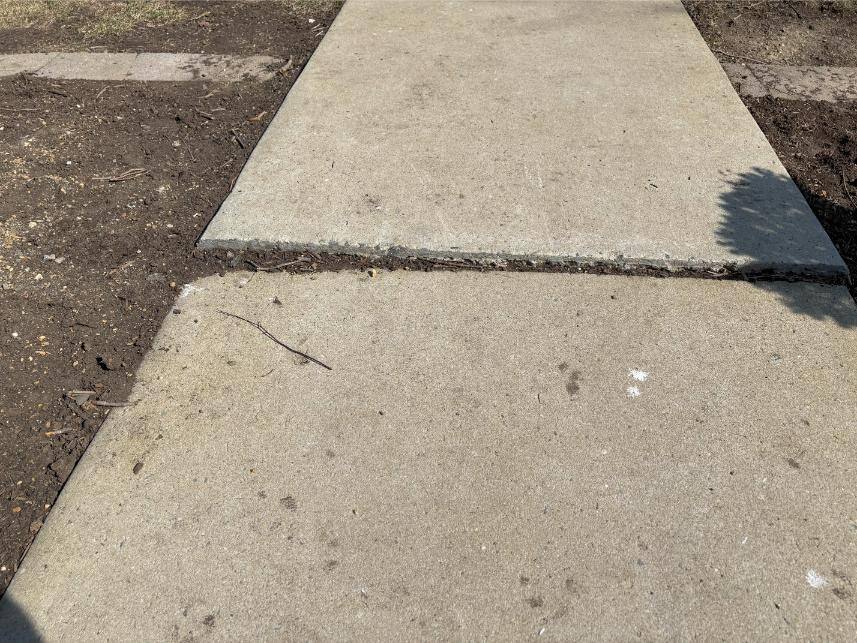 Close-up of sidewalk needing polyjacking repair. The two slabs of concrete are not level.